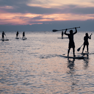 Persone sulla tavola da SUP al tramonto